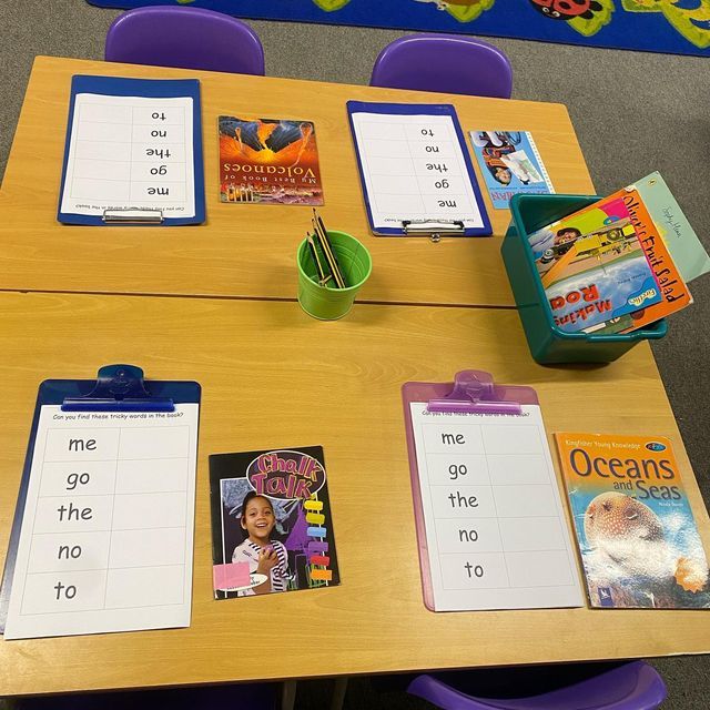 a table with some books on it and two chairs next to the table are purple plastic chairs