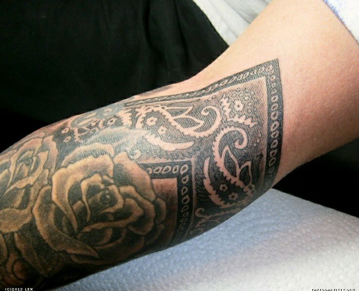 a man's arm with tattoos on it and a rose in the center is shown