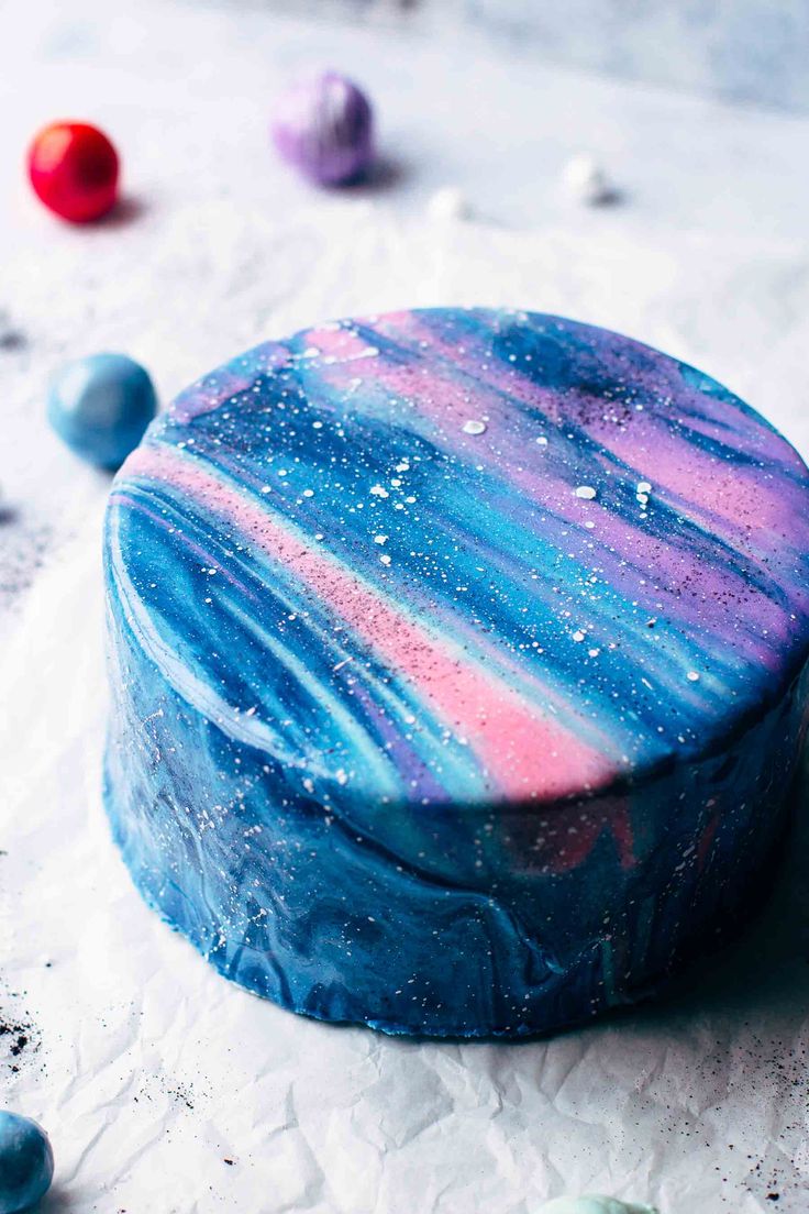 a blue, pink and purple marbled round box sitting on top of white paper