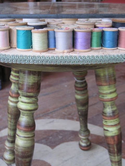 several spools of thread sitting on top of a wooden table in front of a window