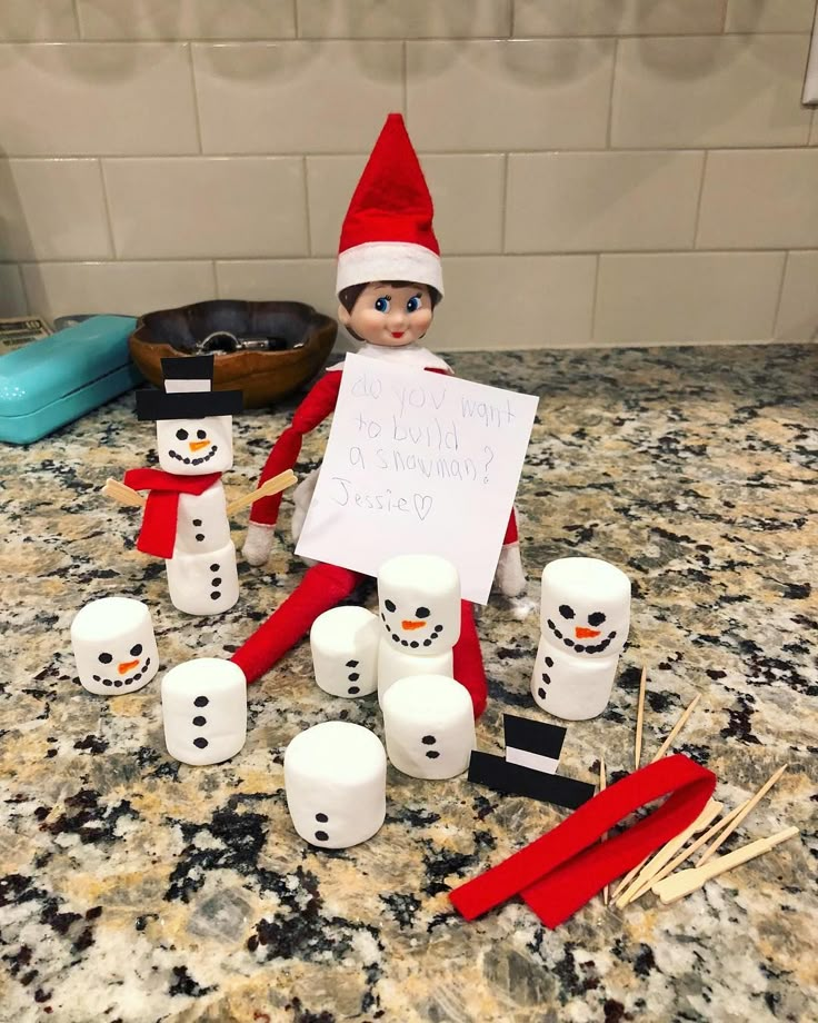 an elf holding a sign next to marshmallows and toothbrushes on a counter