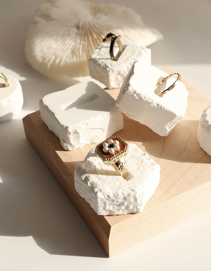 several pieces of jewelry sitting on top of a piece of wood next to seashells