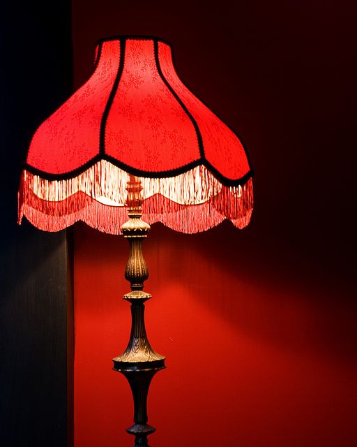 a lamp that is sitting on top of a wooden table next to a red wall