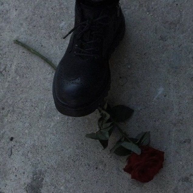 a pair of black boots and a red rose on the ground next to a shoe