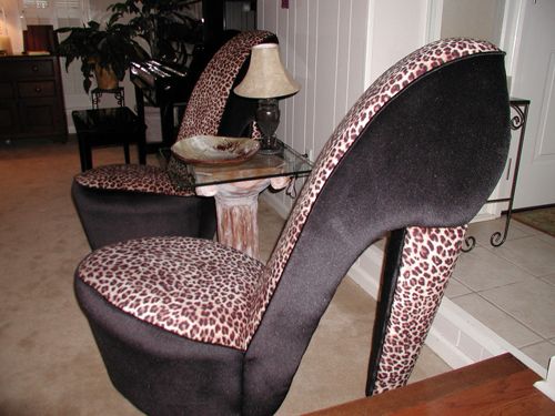 a leopard print high heeled chair sitting in front of a table with a lamp on it