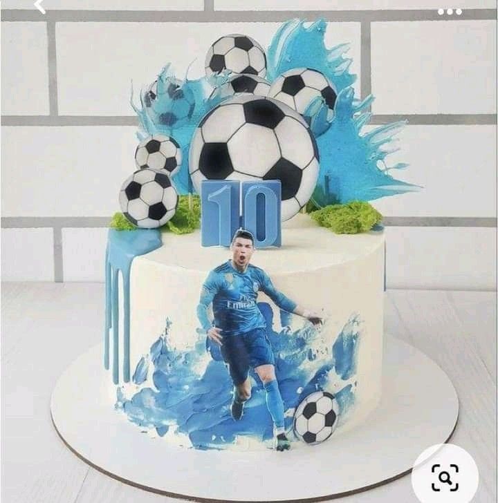 a birthday cake with a soccer player on the top and blue paint splatters around it