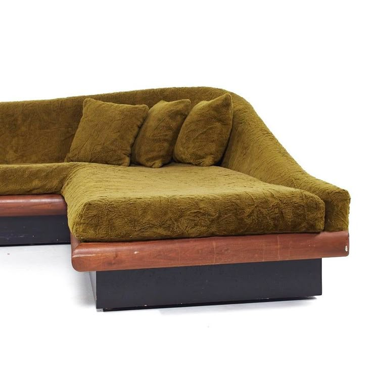 a couch that is sitting on top of a wooden stand with pillows in front of it