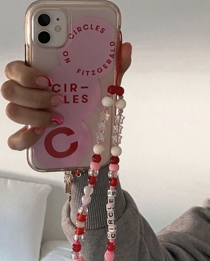 a person holding up a cell phone case with beads on it