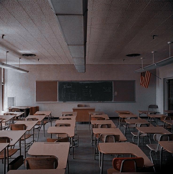 an empty classroom with wooden desks and chalkboard on the wall in front of it