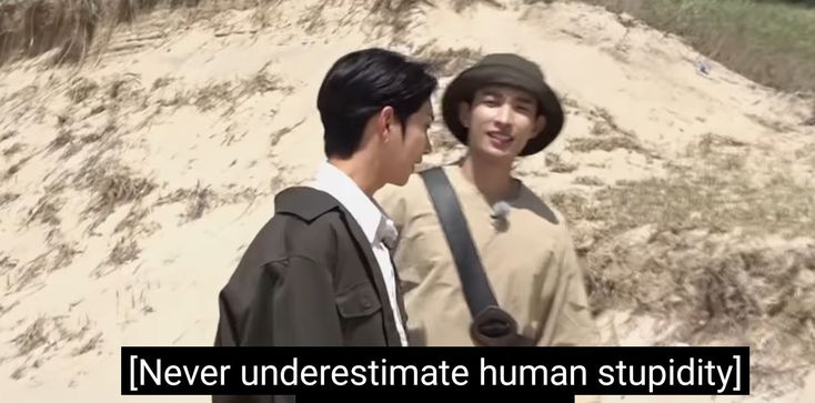 two young men standing next to each other on a sandy beach with the caption never underestimate human stupidly