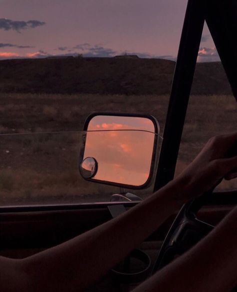 a person is sitting in the driver's seat of a car as the sun sets