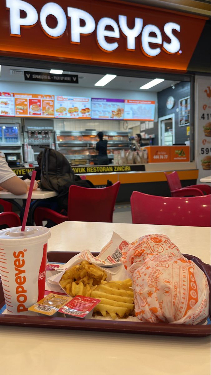 a tray that has some food on it and people sitting at the table in the background