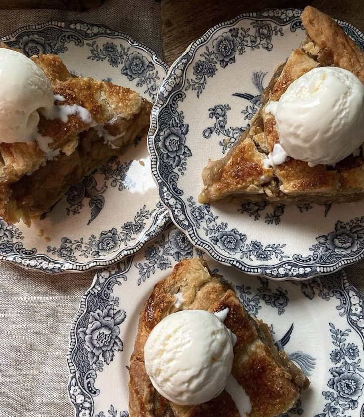 three plates topped with slices of pie covered in ice cream on top of a table