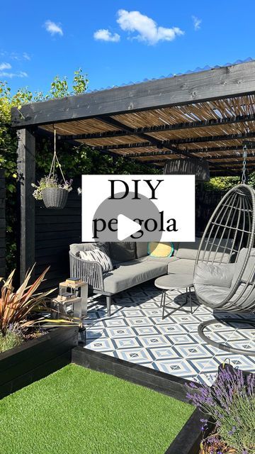 an outdoor living area with furniture and plants on the grass, in front of a wooden pergola