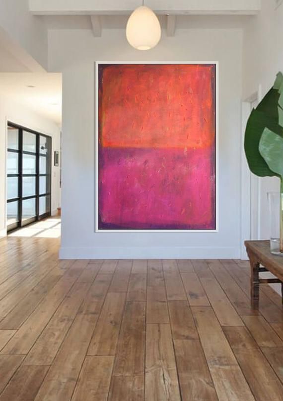 a large painting hanging on the wall next to a wooden bench in an empty room