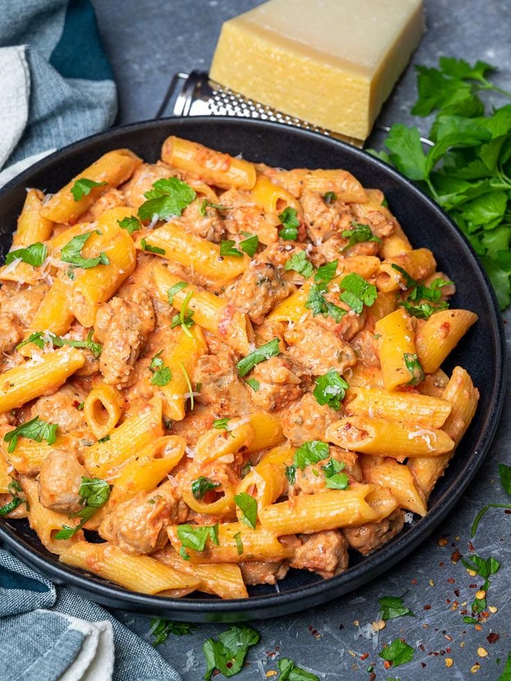 pasta with meat sauce and parsley in a black bowl on a blue tablecloth