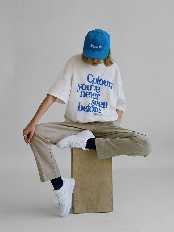 a man sitting on top of a wooden block wearing a blue hat and t - shirt