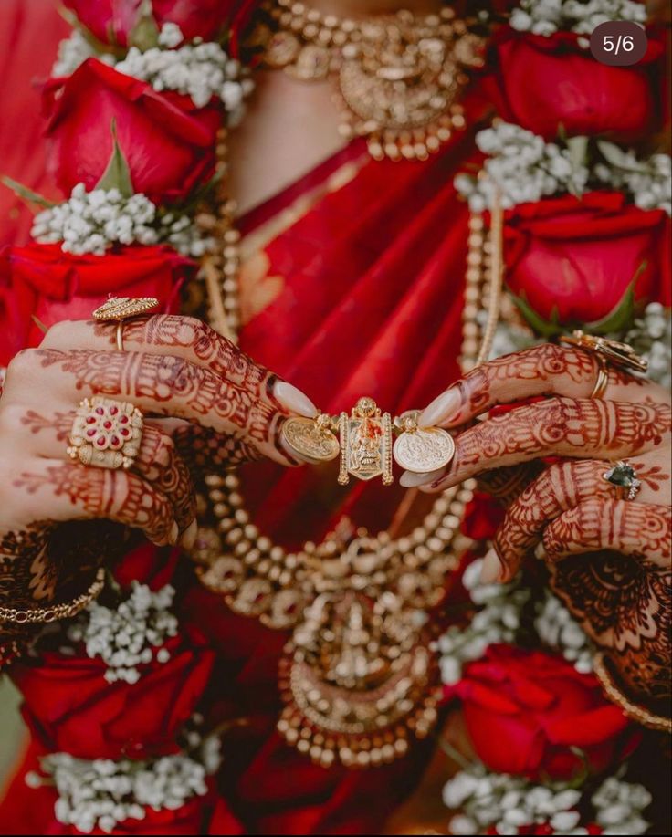 a woman in red dress holding her hands with henches and jewelry around her neck