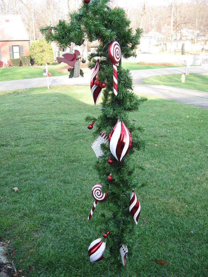 a christmas tree with candy canes hanging from it's branches in the grass