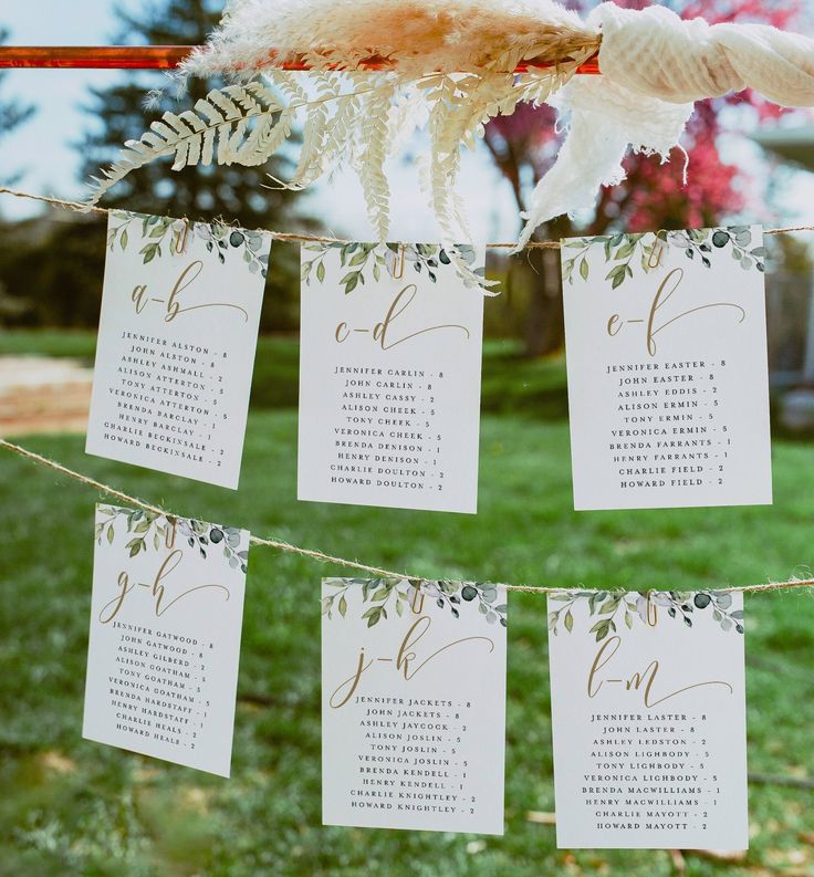 wedding seating cards hanging from a line in the grass