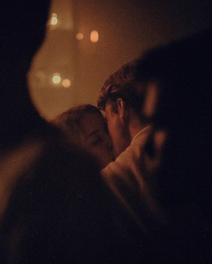 two people are kissing in the dark with their hands on each other's shoulders