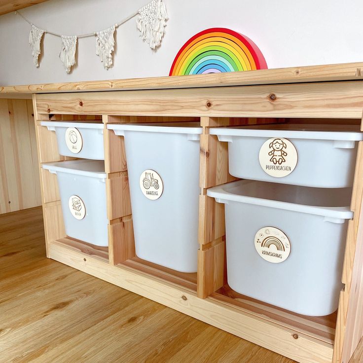 three white plastic buckets sitting on top of a wooden shelf next to a rainbow