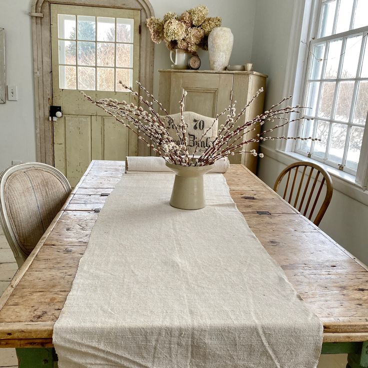 a table with a vase on top of it and flowers in front of the table