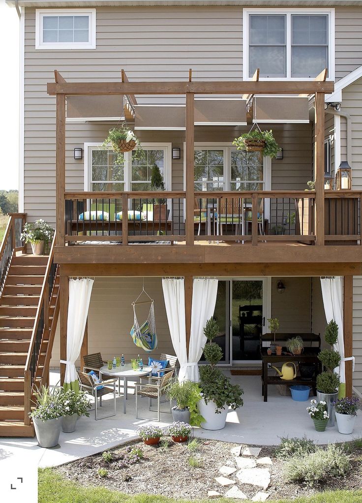 a deck with curtains on it and some potted plants