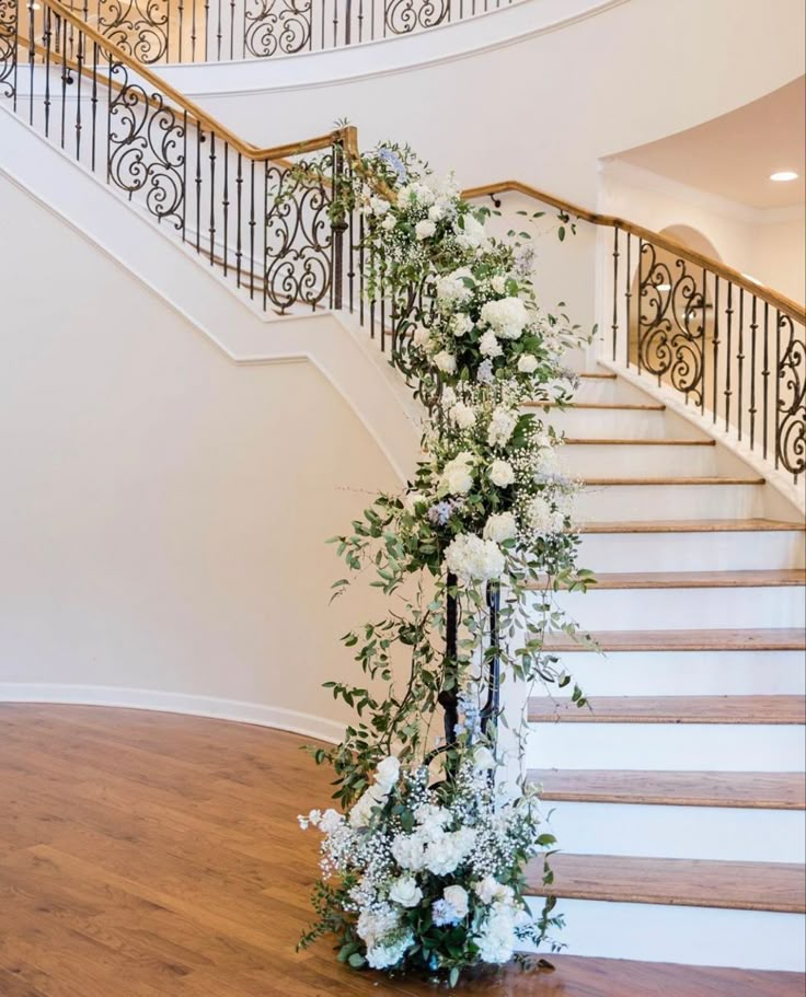 a staircase decorated with white flowers and greenery