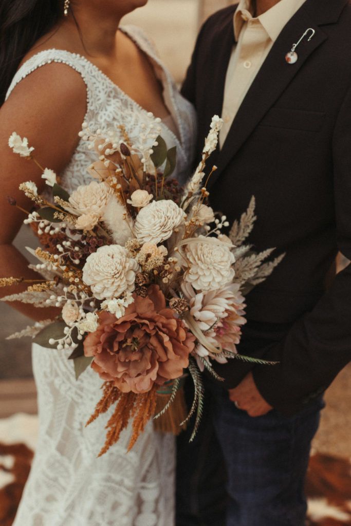 a man and woman standing next to each other in front of a building holding flowers