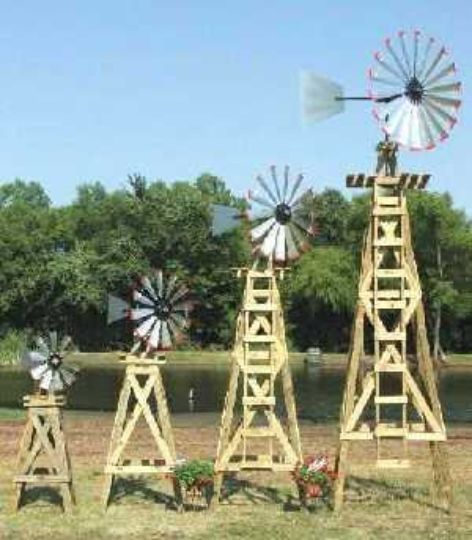 three wooden windmills sitting on top of a grass covered field