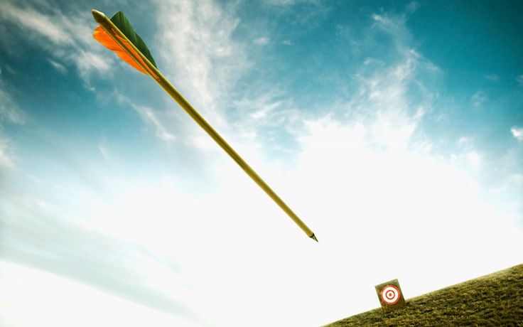 an arrow is flying in the air over a field with a target on it's tip