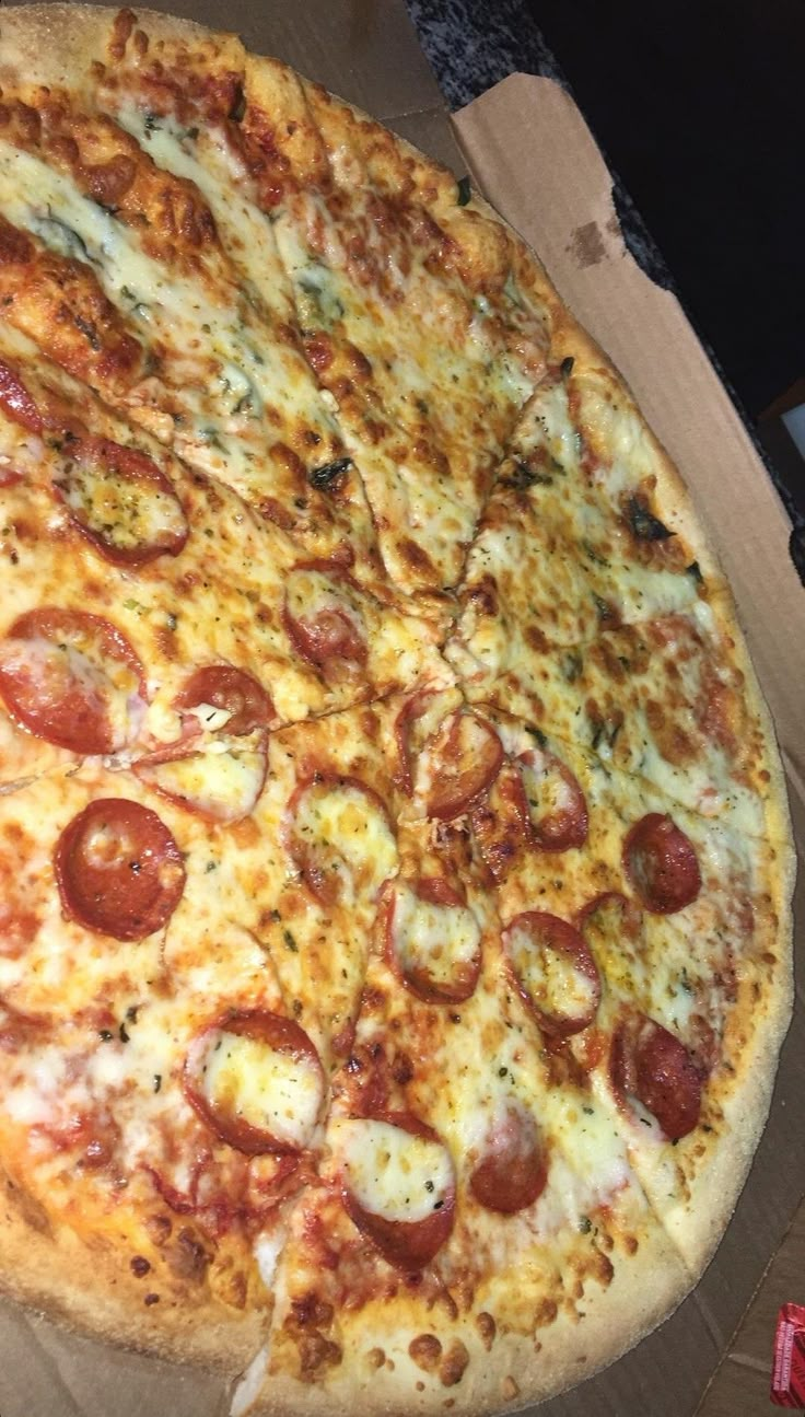 a large pepperoni pizza sitting on top of a cardboard box