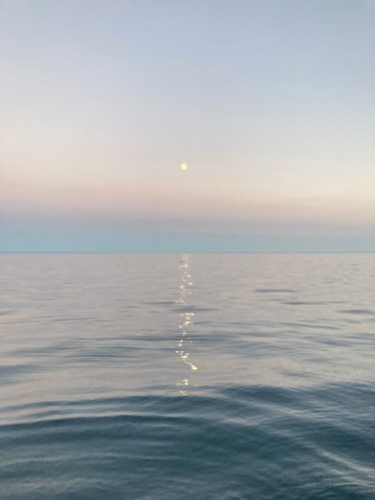 the sun is setting over the ocean as seen from a boat on the water's surface