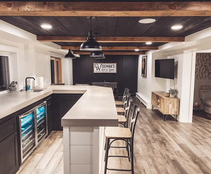 a kitchen with an island and bar stools next to it, in the middle of a room