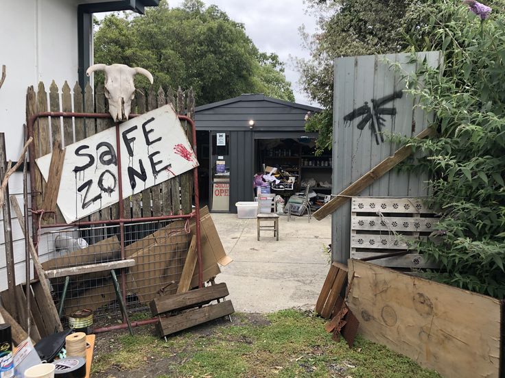 an outdoor area with junk and signs on the fence, including a goat skull head