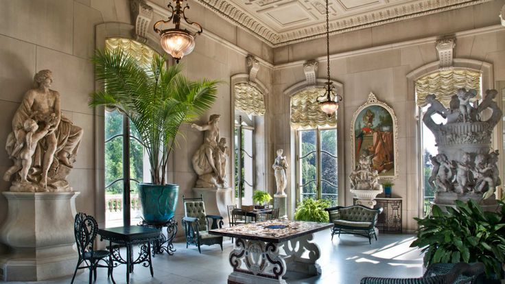 an ornately decorated room with statues and plants in the center, along with chandeliers