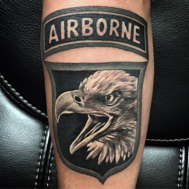 an eagle with the words airborne on it's arm and in front of a shield