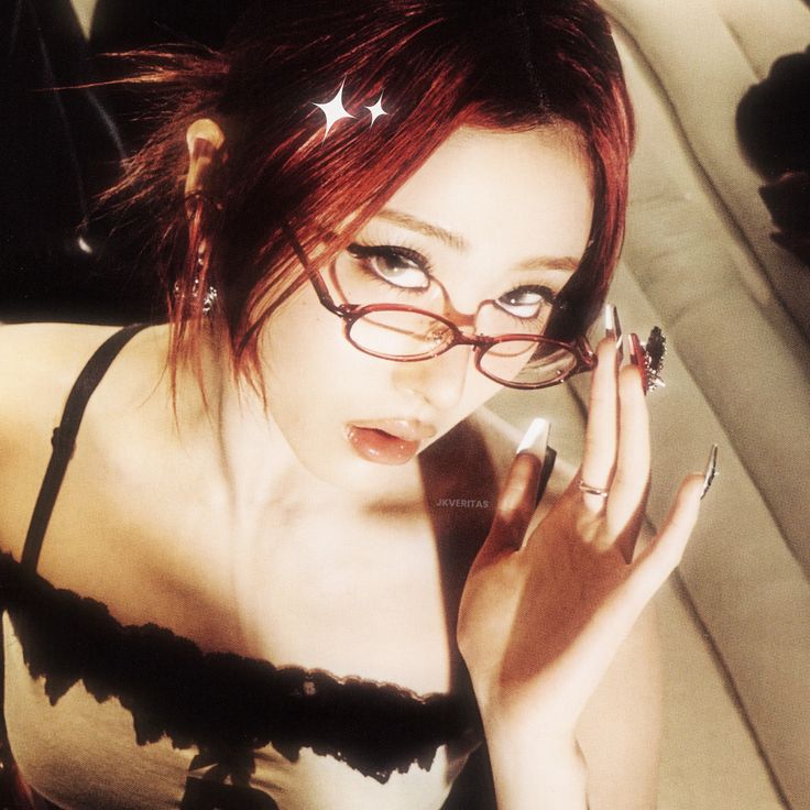 a woman with red hair and glasses talking on a cell phone