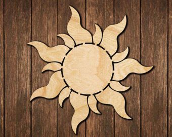 a wooden sun cutout sitting on top of a wooden floor next to a wall