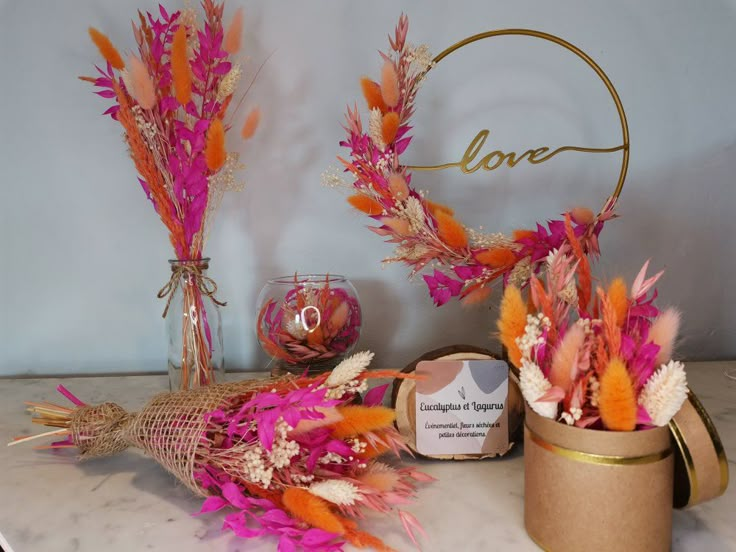 two vases filled with flowers on top of a marble counter next to a love sign