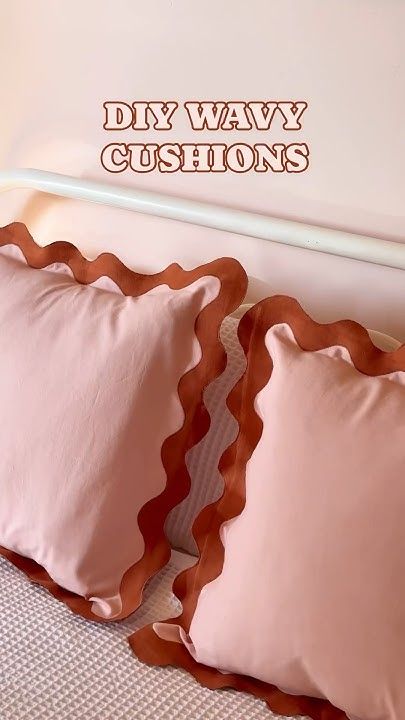 two pink pillows sitting on top of a bed next to a white headboard with the words diy way cushions