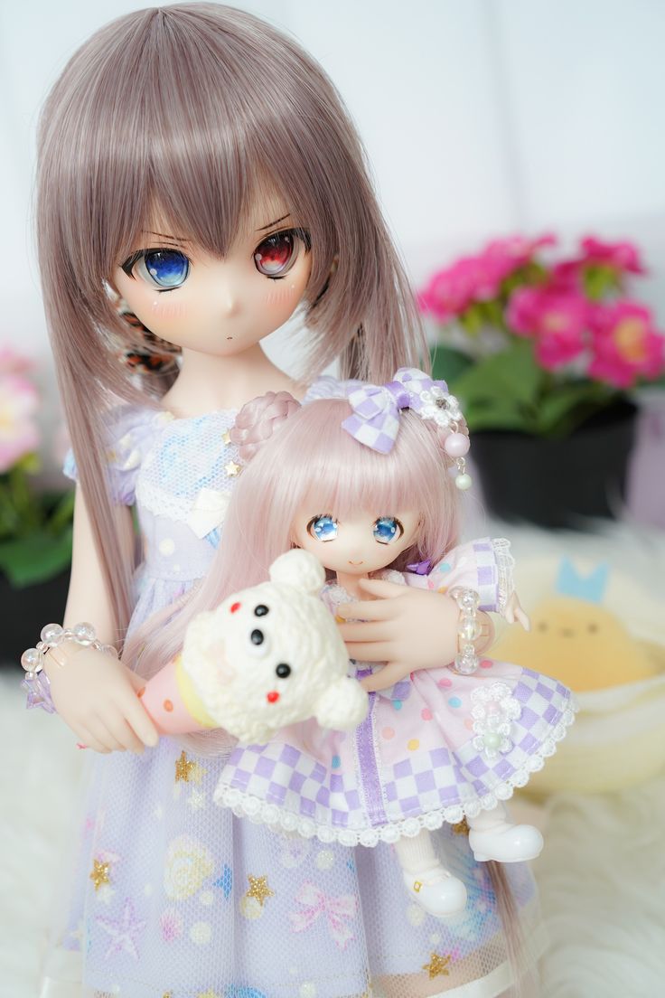 a doll is holding a stuffed animal in her hand while standing next to another doll