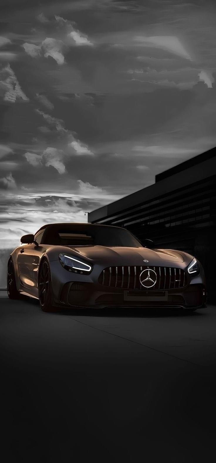 a black and white photo of a mercedes sports car in front of a dark building