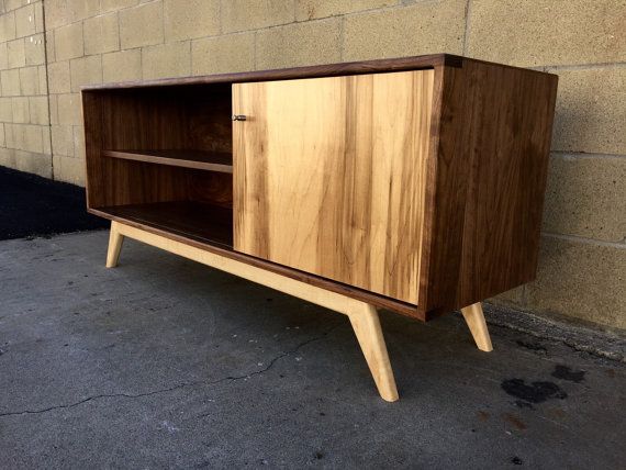 a wooden cabinet sitting on top of a cement floor next to a brick wall,