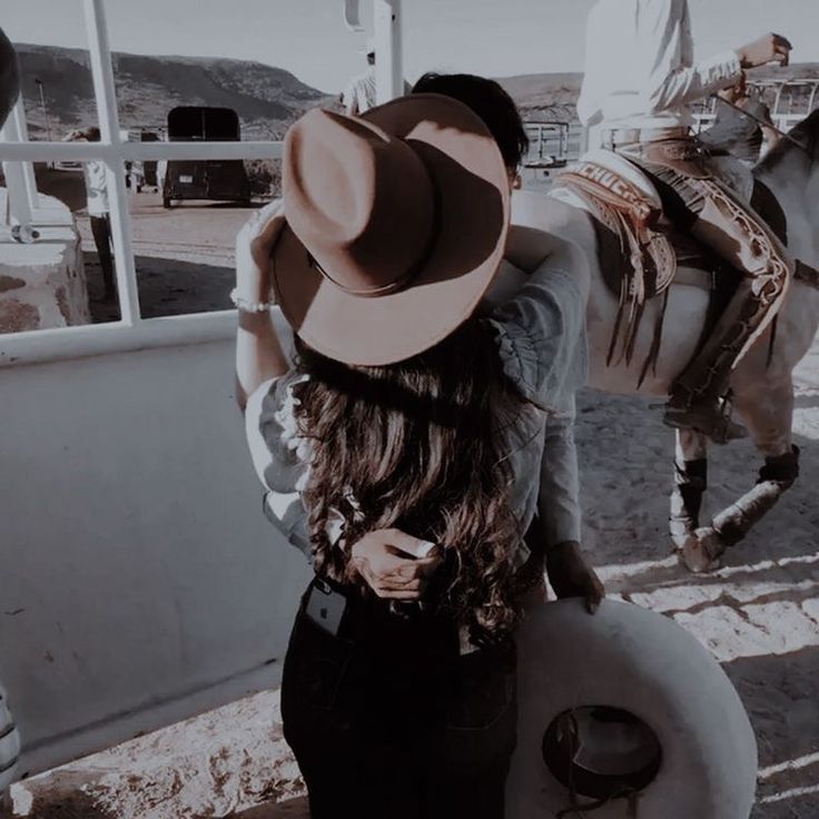 a woman standing next to a horse with a saddle on it's back,