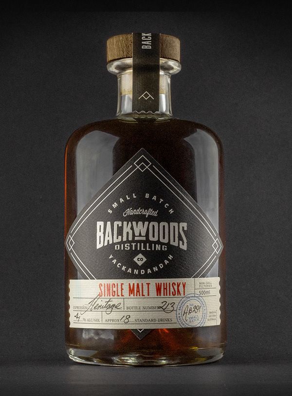 a bottle of backwoods single malt whiskey sitting on a table with a black background