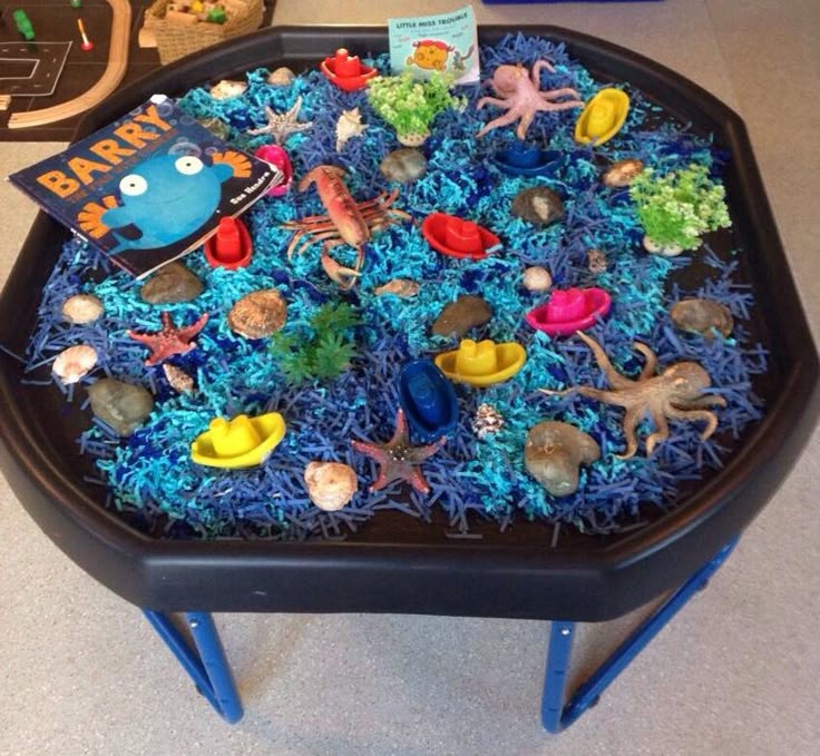 a black tray with blue grass and sea animals on it is sitting on the floor