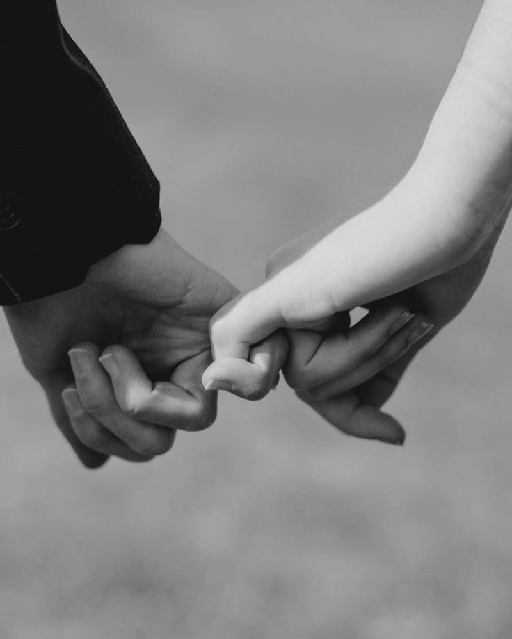 black and white photograph of two people holding each other's hands with their fingers