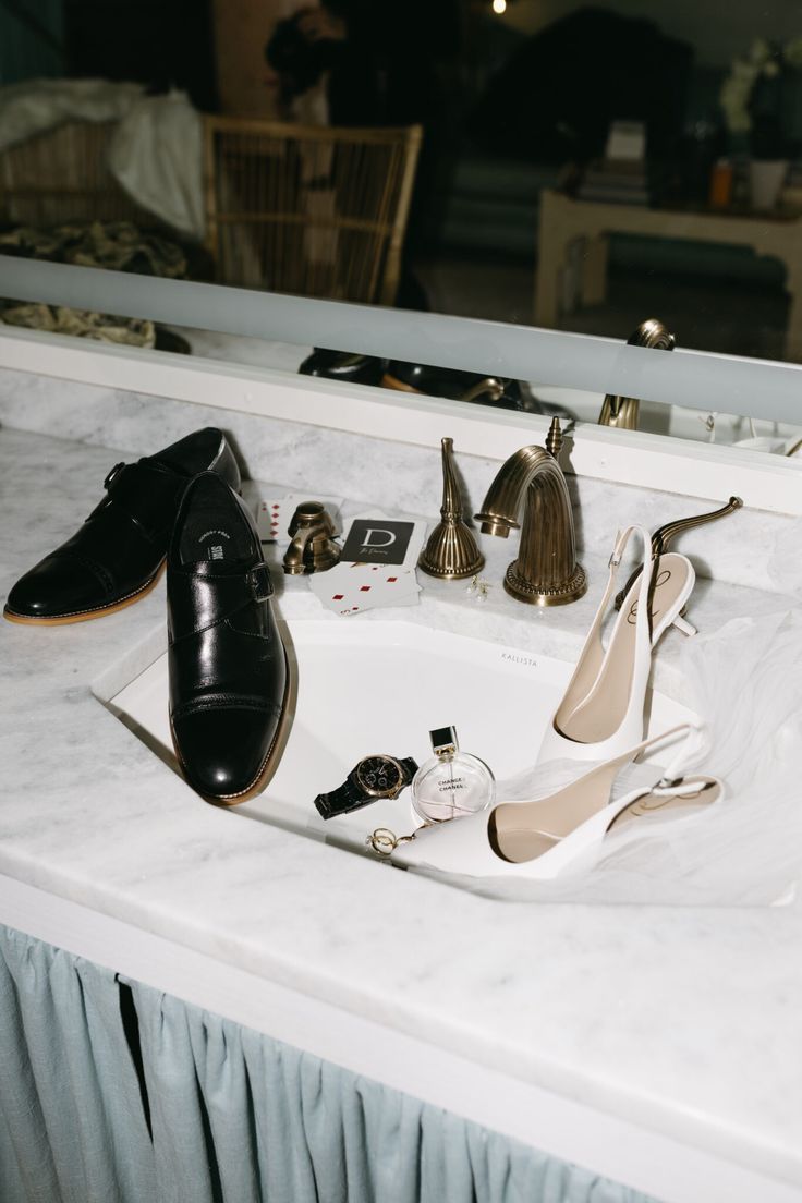 a pair of black shoes sitting on top of a bathroom sink next to a mirror